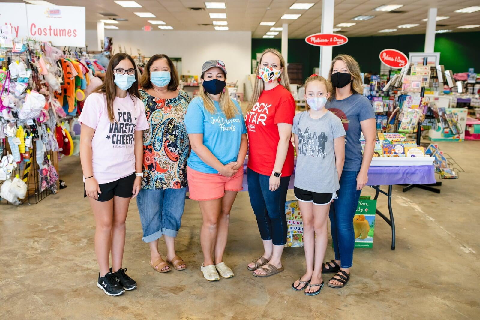 A group of shoppers wearing face masks for safety reasons gathers together at the sale to shop.