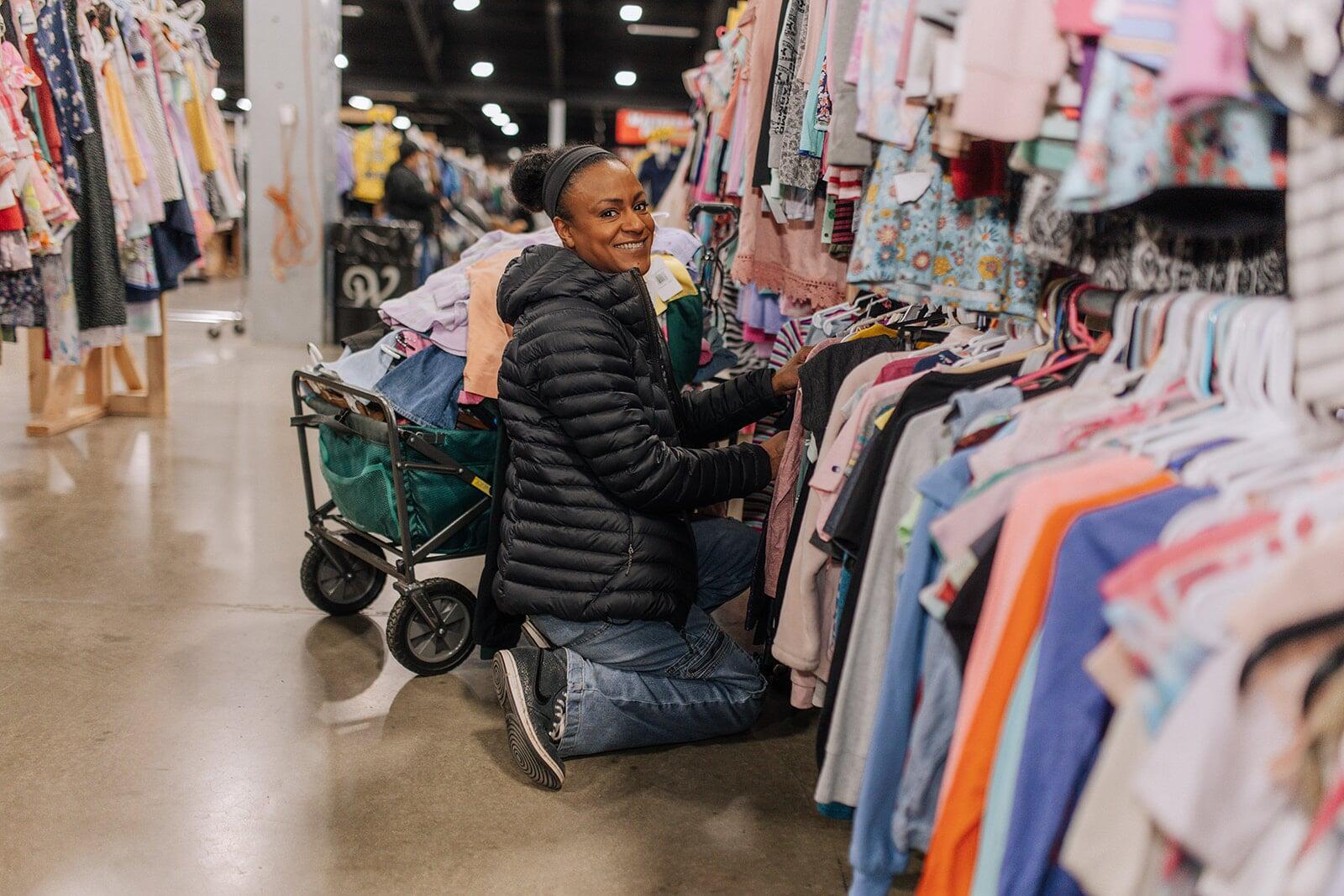 A mom and her four-year-old son stand with their masks and shopping bag in front of baskets of books and costumes.