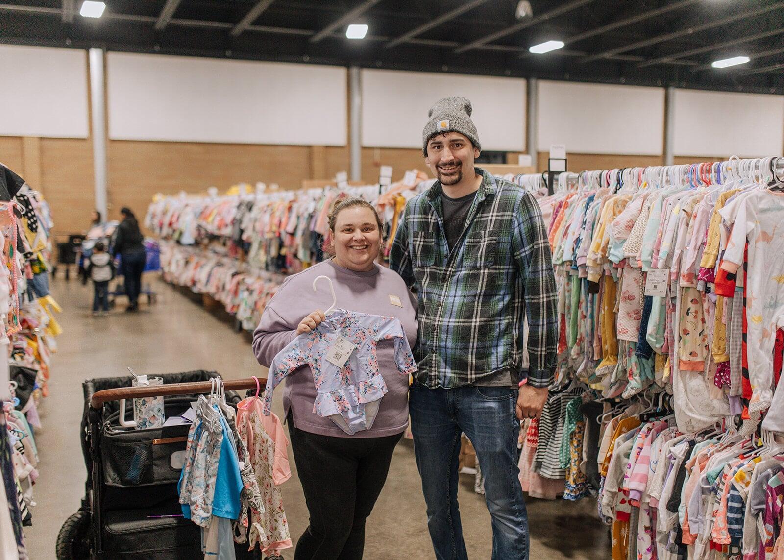Mom and Dad smile while showing us their selections of  baby girl clothing
