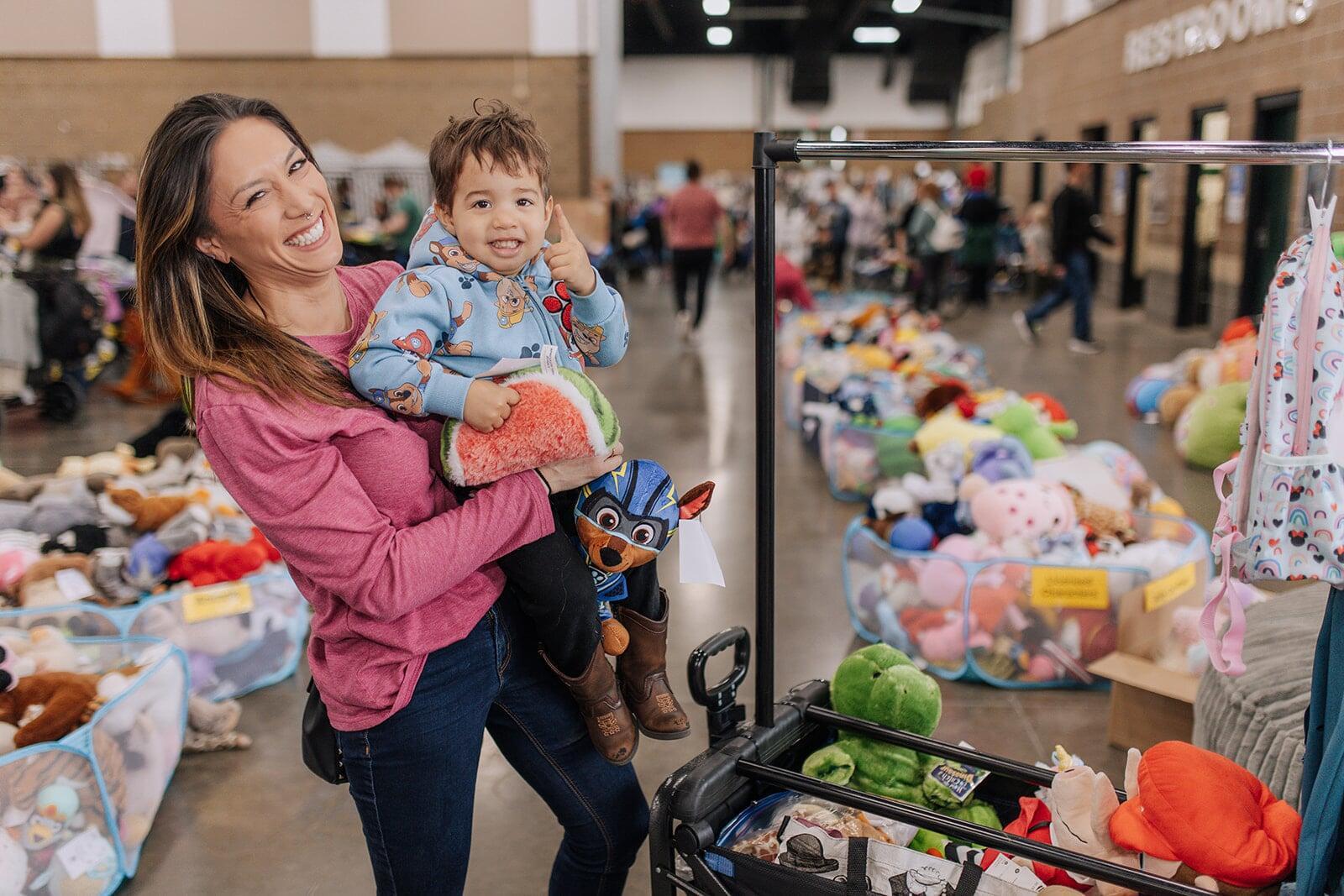 Smiling mother holds toddler son as they shop